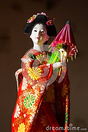 Japanese female kimono doll wearing red paper umbrella with flowers in hair and green glowing tritium trinket Stock Photo